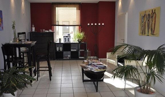 Modern eingerichteter Wartebereich mit Pflanzen, Kunstwerken und gemütlicher Sitzecke.