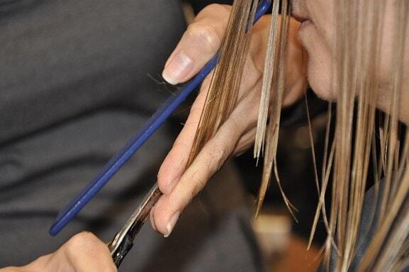 Friseur schneidet nasses Haar mit Schere und Kamm im Friseursalon professionell.