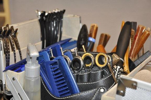 Friseurbedarf mit Scheren, Kämmen, Bürsten und Haarklammern in einer Werkzeugbox.